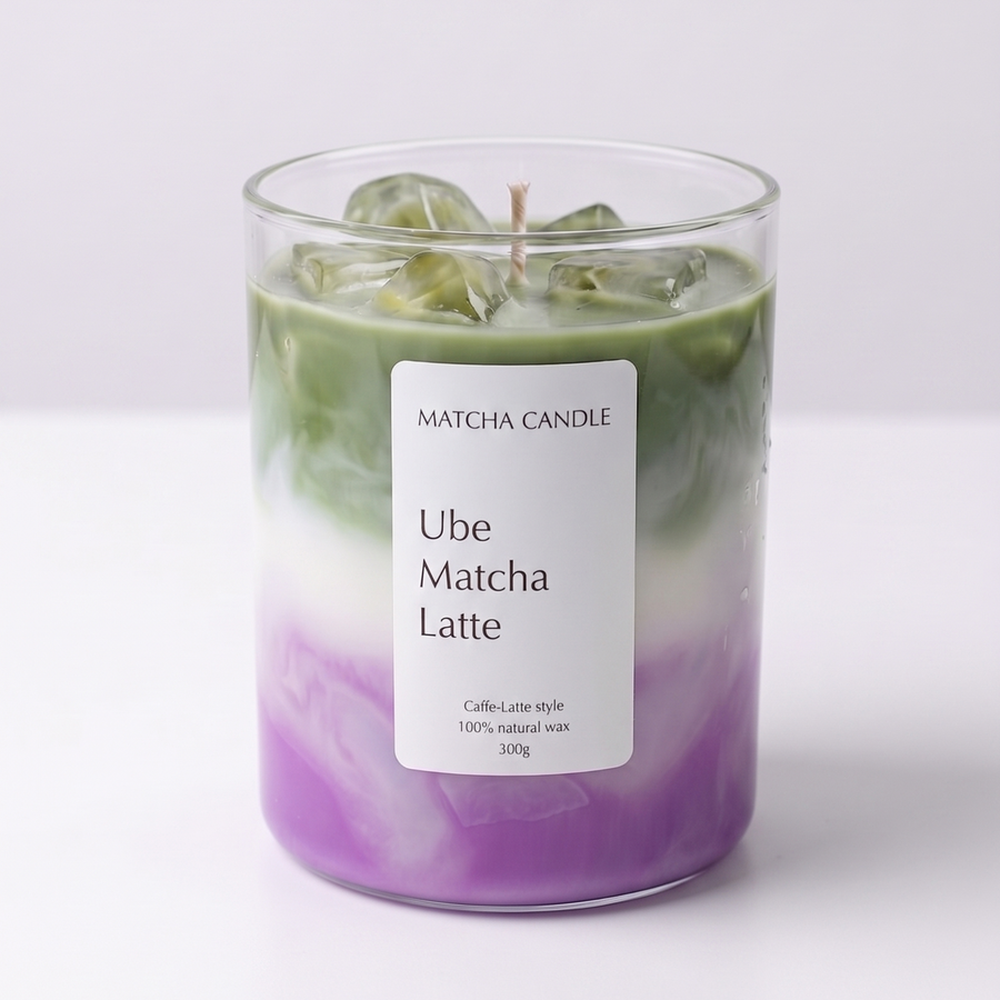 A glass jar candle with a white label reading 'MATCHA CANDLE Ube Matcha Latte' on a clean white background. The candle wax shows a layered color story with a purple base, a white middle band, and green on top, with ice cubes visible inside the glass.